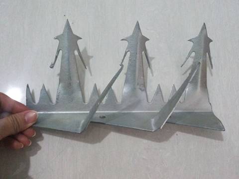 Several fingers hold a row of big size wall spikes with galvanized surface treatment.