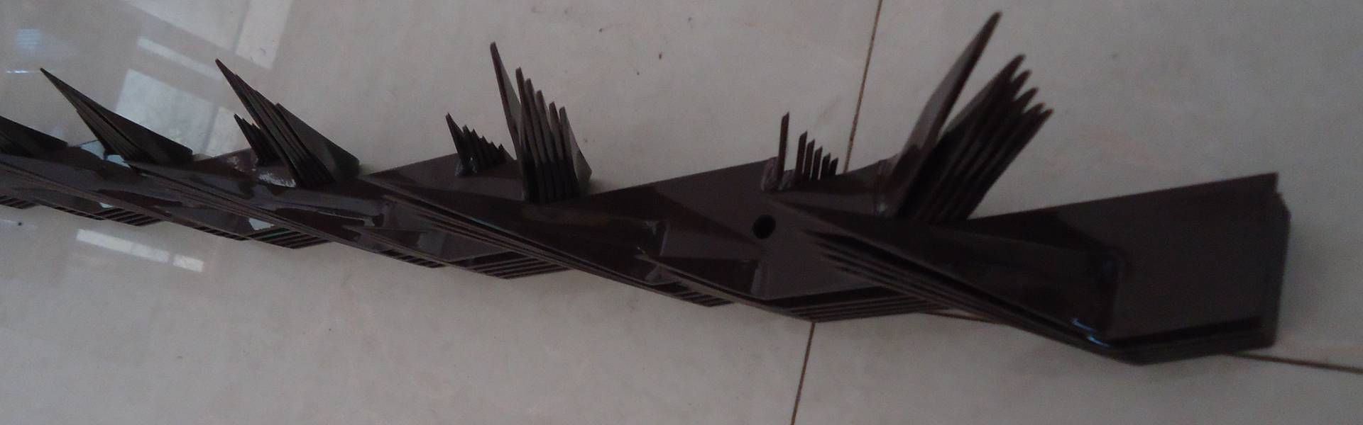 A piece of PVC coated brown security spike with leaning middle size spikes.