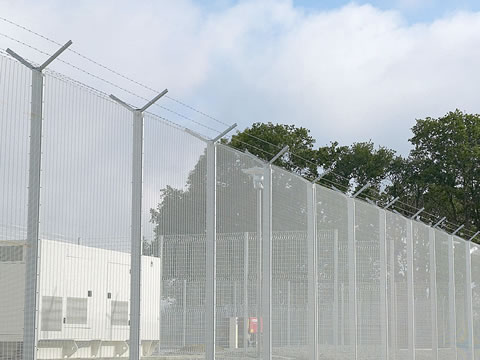 With barbed wire topping, a galvanized welded wire security fence is installed at a power station.