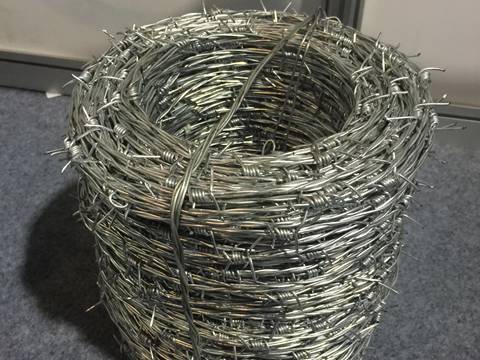 Side view of a coil of stainless steel barbed wire and fastened by stainless steel wire on the floor.