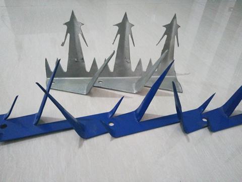 A row of wall spikes made of stainless steel and a row of wall spikes painted blue color.